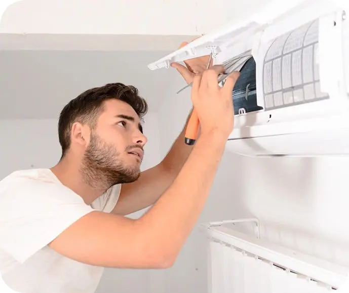 A man is fixing the air conditioner on his wall.