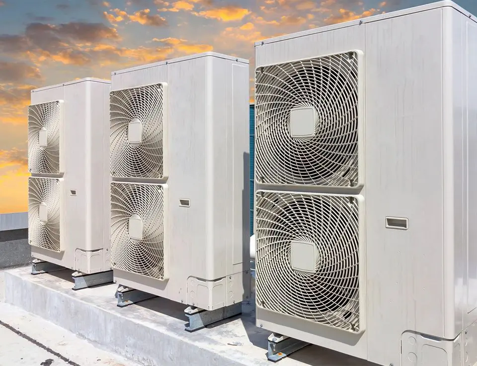 A row of air conditioners sitting on top of concrete.