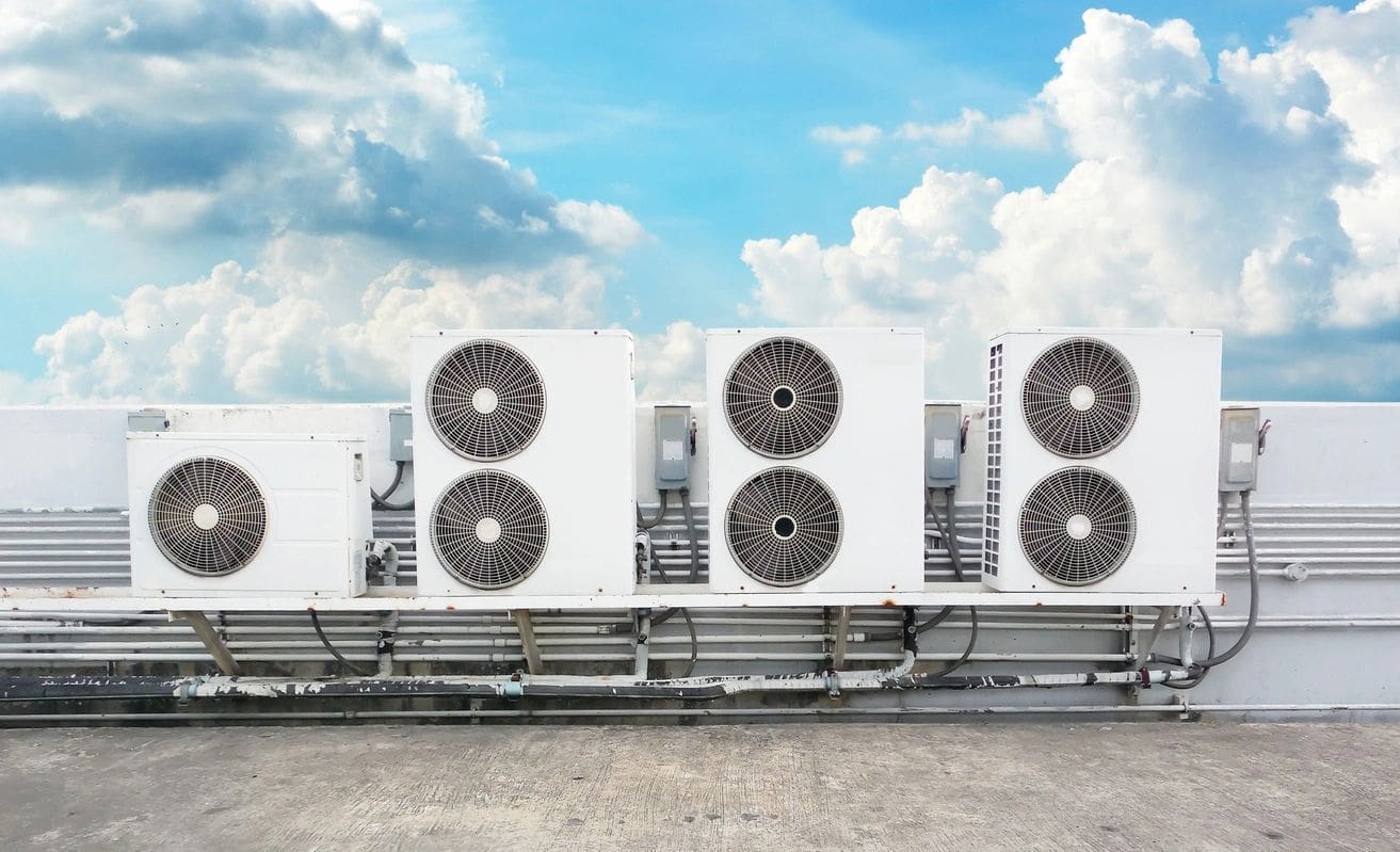 A row of air conditioners sitting on top of a building.